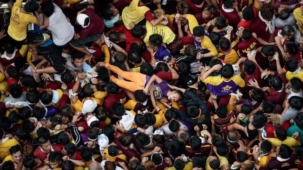 A young woman is carried aloft and away from the crush by the crowd. Manila, Philippines, 9 January 2017.