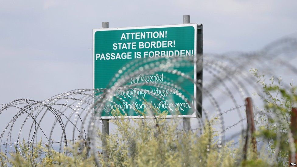 A warning sign is pictured behind a barbed wire barricade erected by Russian and Ossetian troops along Georgia's de-facto border with its breakaway region of South Ossetia, 14 July 2015
