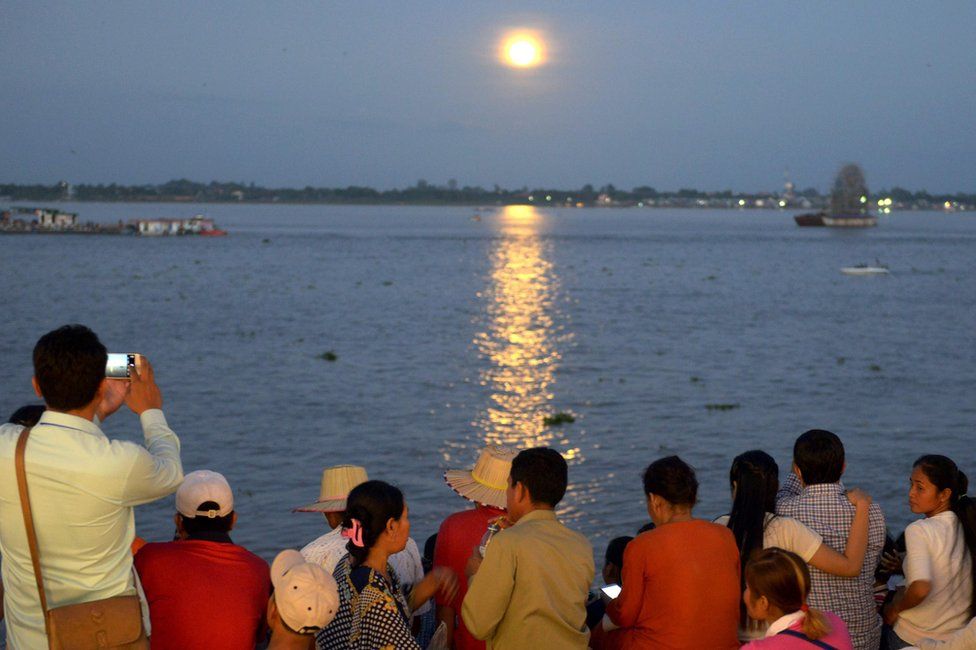 Cambodian people watch as the "supermoon" rises over the Mekong river in front of the Royal Palace in Phnom Penh on November 14, 2016