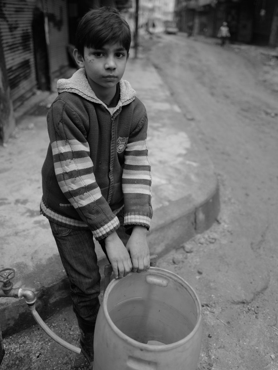 Boy collects water for his family in eastern Aleppo