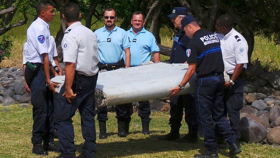 French gendarmes and police carry a large piece of plane debris