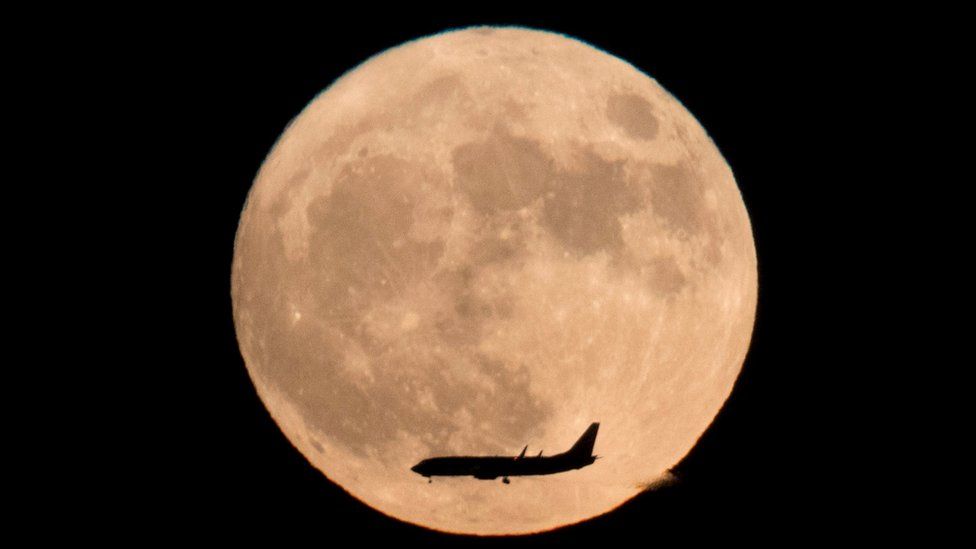 A jet plane flies across the moon seen from Beijing, China, Monday, Nov. 14, 2016