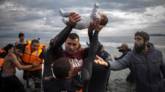 Un voluntario ayuda a un grupo de migrantes a desembarcar en la isla de Lesbos, en Grecia. 