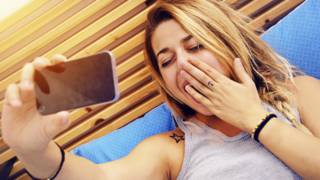 Mujer haciéndose un selfie en la cama