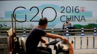 G20峰会将于9月初在中国杭州举行。图为一名骑自行车的杭州市民经过G20峰会的宣传画。