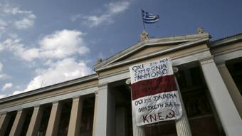 Banco con la bandera de grecia y un cartel de protesta