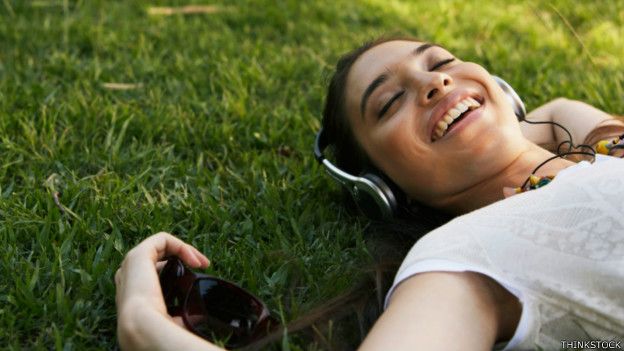 Una persona disfrutando de música echada en el pasto