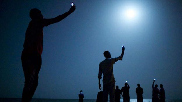 Inmigrantes intentan captar señal para sus teléfonos celulares