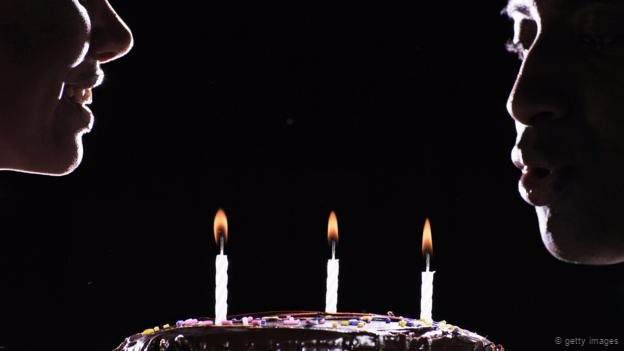 Un hombre y una mujer frente a un pastel de cumpleaños