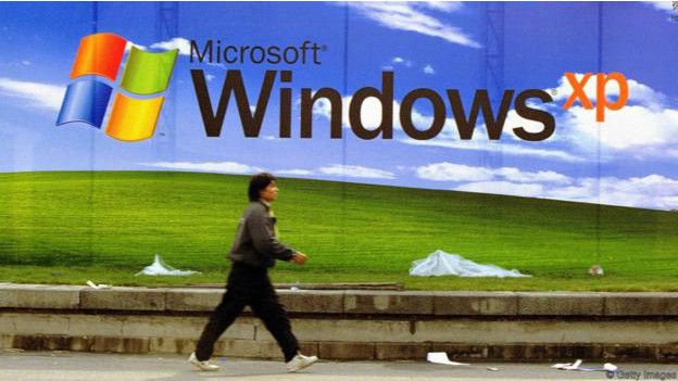 Una persona caminando frente a un poster de Windows XP