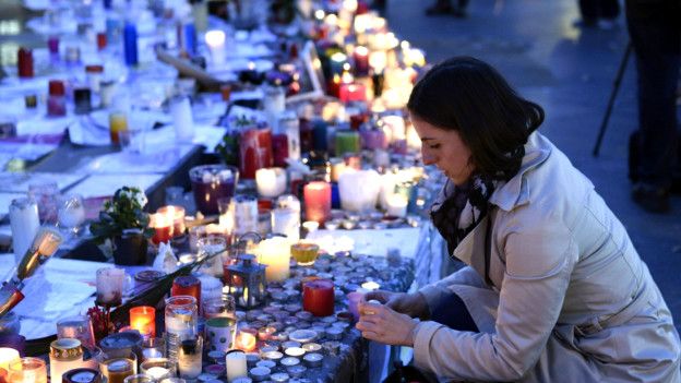 Una mujer enciende una vela en honore a los muertos en los ataques del 13 de noviembre en París.