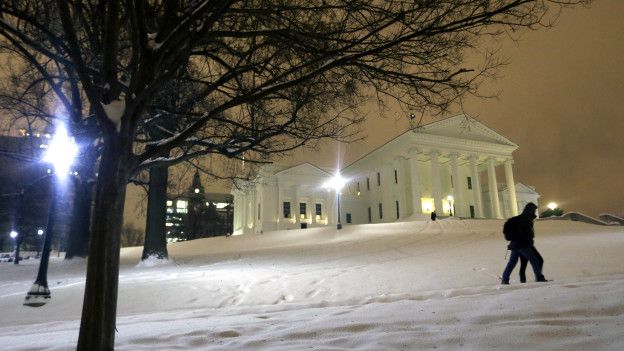 Una pareja camina en la nieve cerca del capitolio de Virginia.