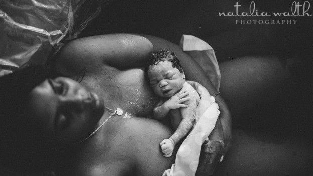 Una mujer sostiene a su bebé recién nacido dentro de una tina