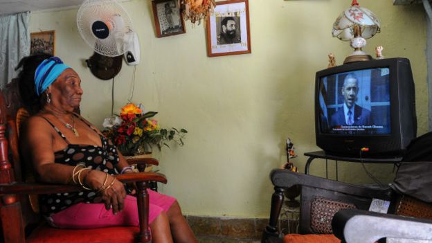 Una mujer cubana mirando a Obama en televisión