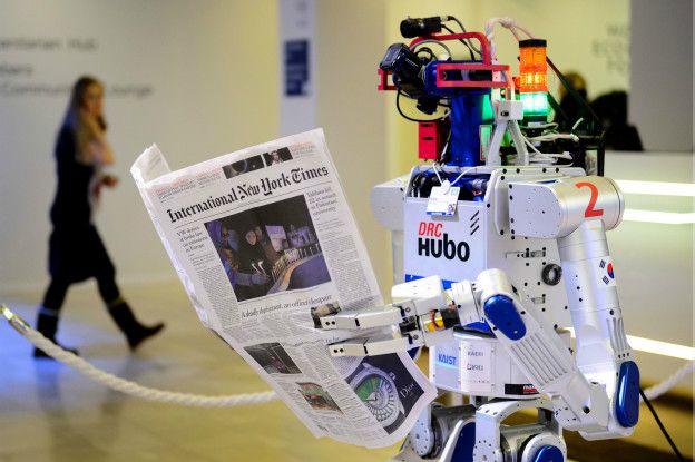 Un robot lee un periódico.