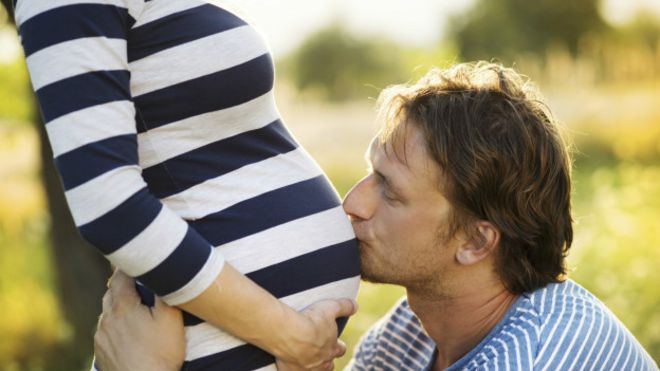 Hombre besando la barriga de una mujer embarazada