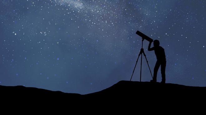 Hombre mirando al cielo por un telescopio