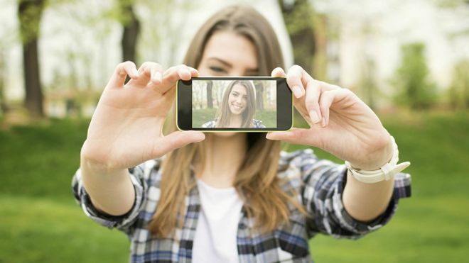 Una joven se toma una auto foto o selfie con su celular