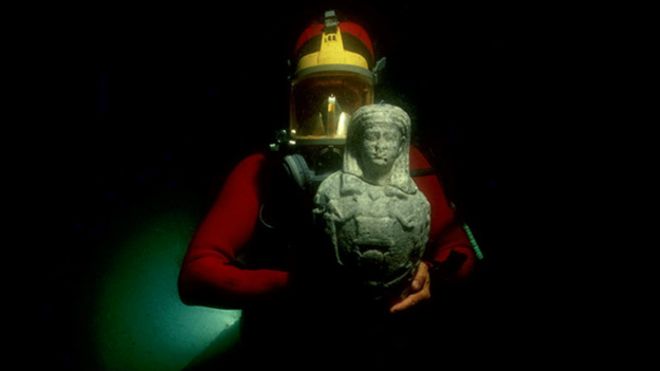 Buzo sostiene estatua del dios egipcio Osiris
