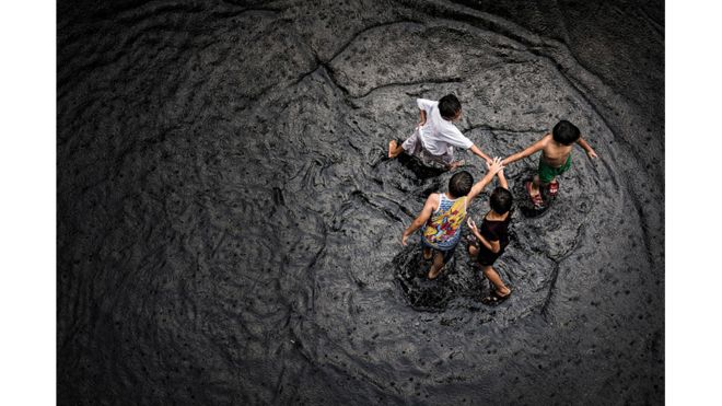 أطفال يلعبون بمياه الفيضانات