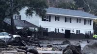 Emergency personnel inspect a damaged home on Hot Springs Road after a mudslide in Montecito