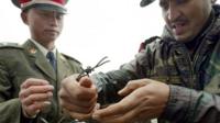 This file photo taken on July 5, 2006 shows a Chinese soldier (L) and Indian soldier placing a barbed wire fence following a meeting of military representatives at the Nathu La border crossing between India and China in India"s northeastern Sikkim state.