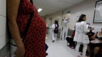 A pregnant woman waits for a routine general checkup, which includes Zika screening.