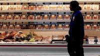 A employee walks by a meat cooler in the grocery section of a Sam"s Club during a media tour in Bentonville, Arkansas, U.S. on June 5, 2014