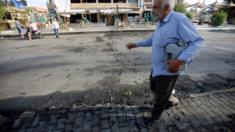 An Iraqi man walks past the site of a car bomb exploded near a cafe in Baghdad. May 30, 2017