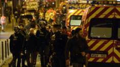 Police forces and rescuers walk through rue Oberkampf near the Bataclan concert hall in central Paris