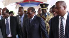 Mr Mugabe surrounded by people including one man in full uniform