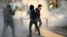 Iranian students run for cover from tear gas at the University of Tehran during a demonstration