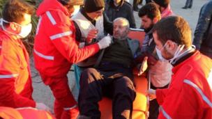 A wounded Syrian, who was evacuated from rebel-held neighbourhoods in the embattled city of Aleppo, is carried by aid workers upon his arrival in the opposition-controlled Khan al-Aassal region, west of the city, on December 15, 2016