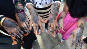 Young Muslim girls show their hands decorated with henna after attending prayers on Eid Al-Fitr