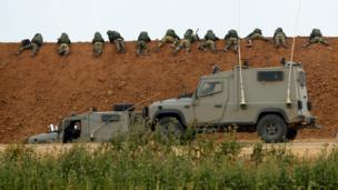 Israeli soldiers lie along an earth barrier along the border with the Gaza strip in the southern Israeli kibbutz of Nahal Oz on March 30, 2018