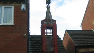 Steve Spill's phone box lifted over the house by a crane