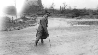 Muirhead Bone crossing a muddy road in France, 1916