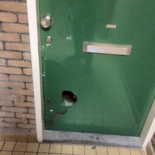 a green door with a hole kicked into it