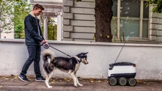 Man walking dog coming face to face with the self-driving robot