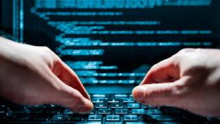 A man typing sinister-looking code into a computer
