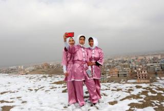 Latifa Safay (right), Hanifa Doosti (centre) and Suraya Rezai (left), students of the Shaolin Wushu club, take a selfie before practicing on a hilltop in Kabul, Afghanistan