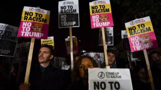 Carteles de "No al racismo, no a Trump" en una marcha