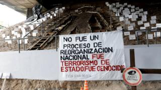 Monumento que tiene un carte con la inscripción "No fue un proceso de reorganización nacional. Fue terrorismo de Estado. Fue Genocidio".