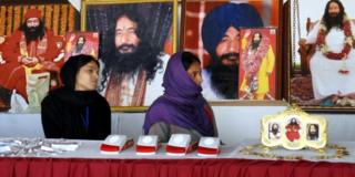 Indian followers of dead guru Ashutosh Maharaj sit in front of posters of him at his ashram on 14 December, 2014