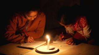 Palestinian refugee girls study by candlelight in their family's makeshift house during a power outage at Khan Younis refugee camp in the southern Gaza Strip (23 April 2017)
