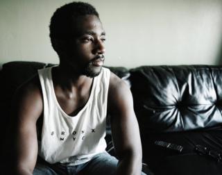 Damani sits on his sofa