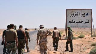 Syrian government forces stand beside a sign saying "Welcome to Deir al-Zour" in eastern Syria on 3 September 2017