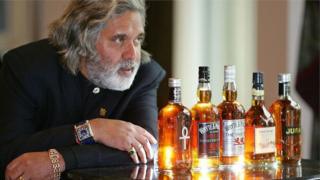 Vijay Mallya in front of alchohol bottles
