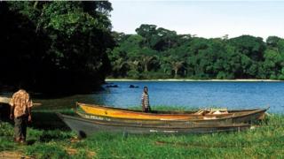 Hombres en las islas Ssese, frente a un bote