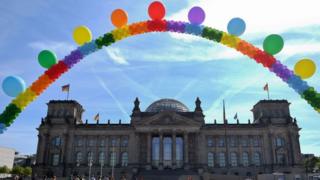A balloon chain in rainbow colours is seen in front of the Reichstag building housing the German parliament (Bundestag) as activists of the LGBT movement demonstrate against homophobia and transphobia on 17 May 2017 in Berlin